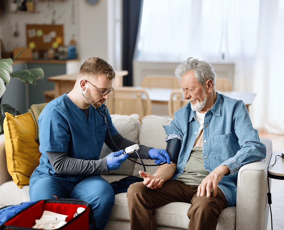 Healthcare worker checking elderly man's blood pressure.
